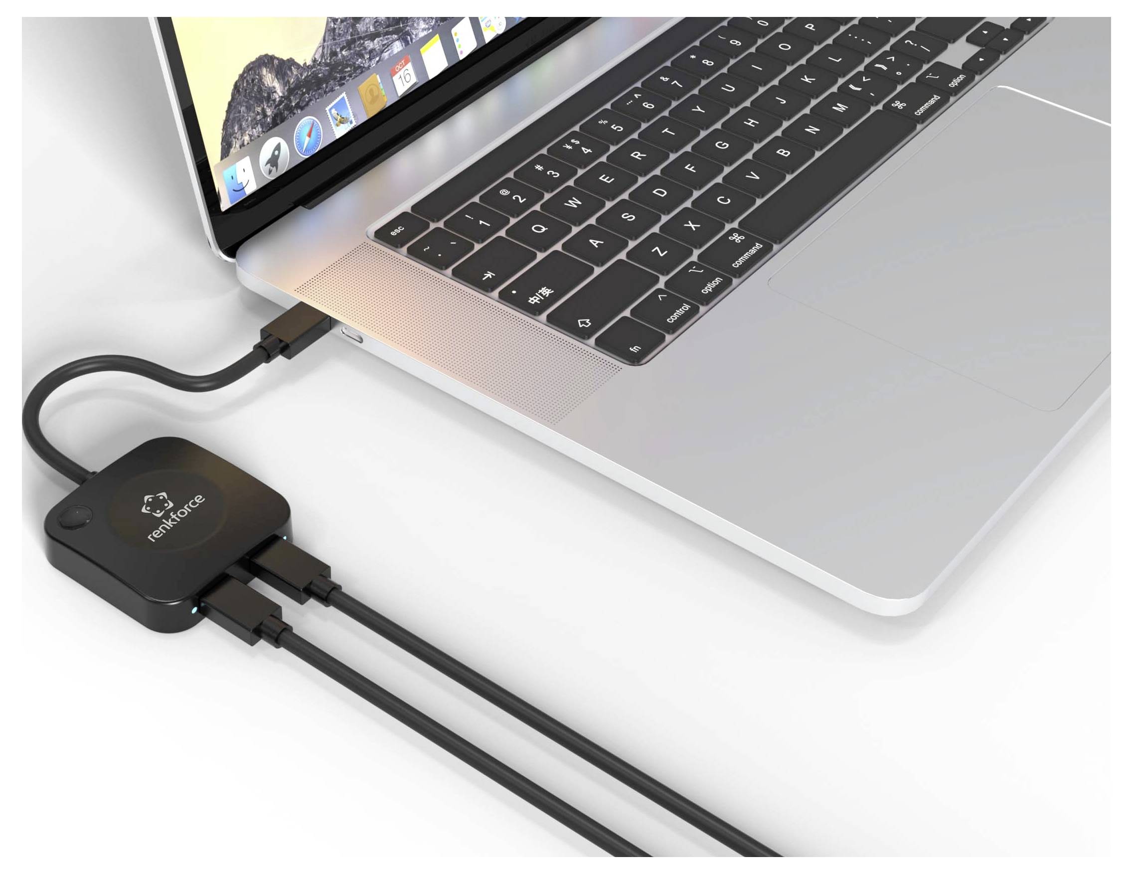 Laptop connected to a black USB-C docking hub with multiple cables attached on a white surface.