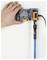 'A hand holding a wall mount next to a mounted electronic device with a blue sensor and black cable, against a white background.'