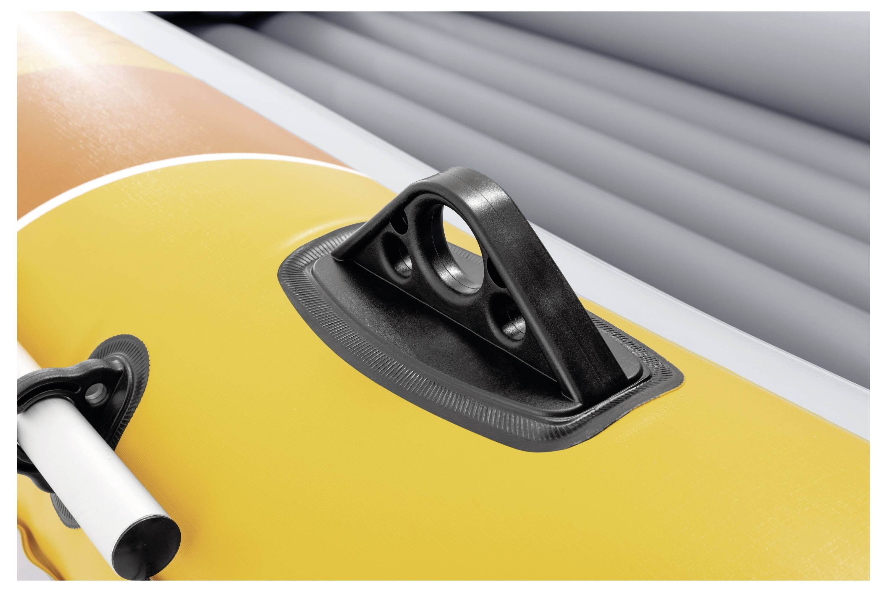 A close-up of an inflatable boat's orange and yellow surface showing a black handle and oar lock mount with part of an oar visible.