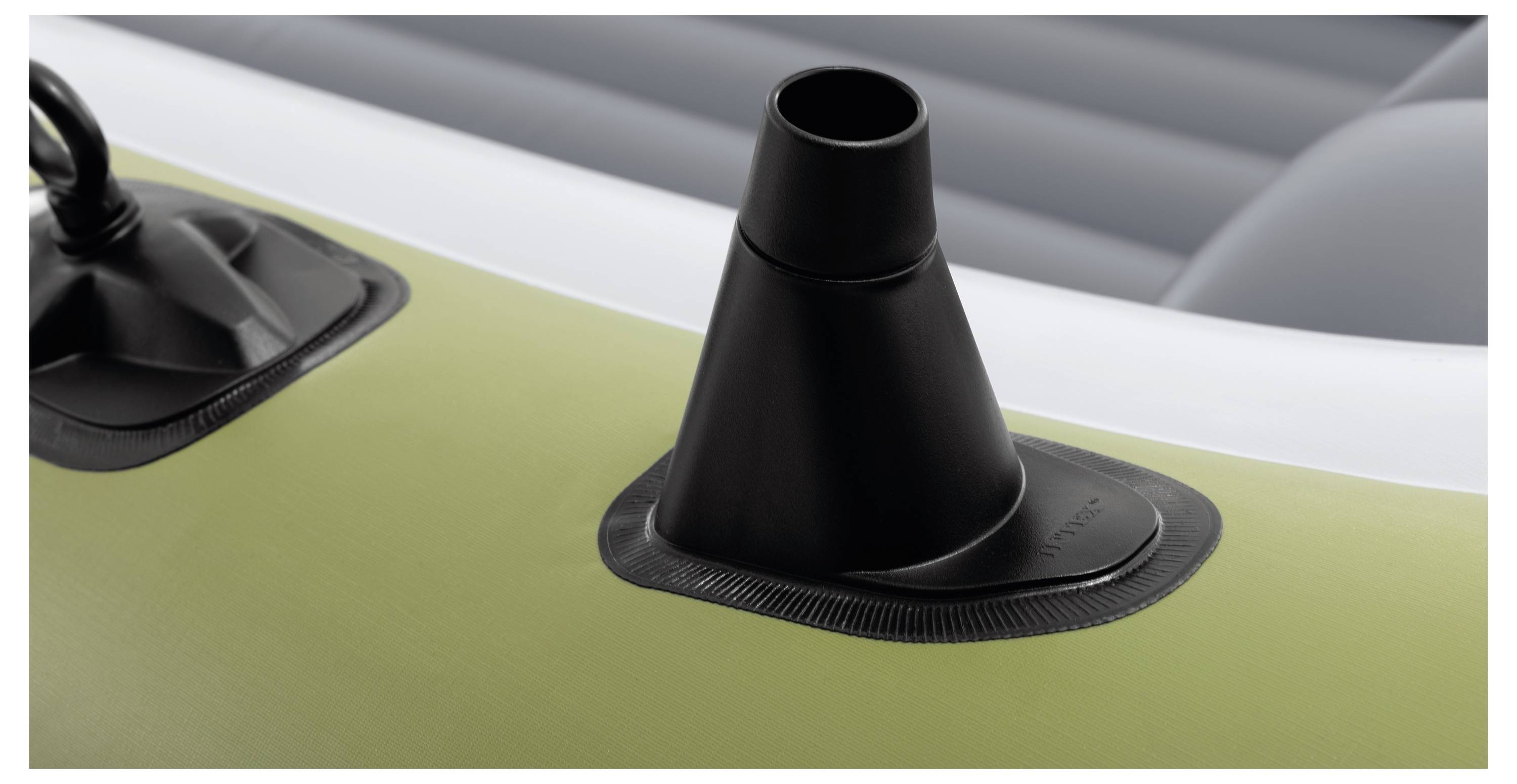 A close-up of a black plastic valve attached to a green inflatable surface, likely part of an air mattress or inflatable boat.