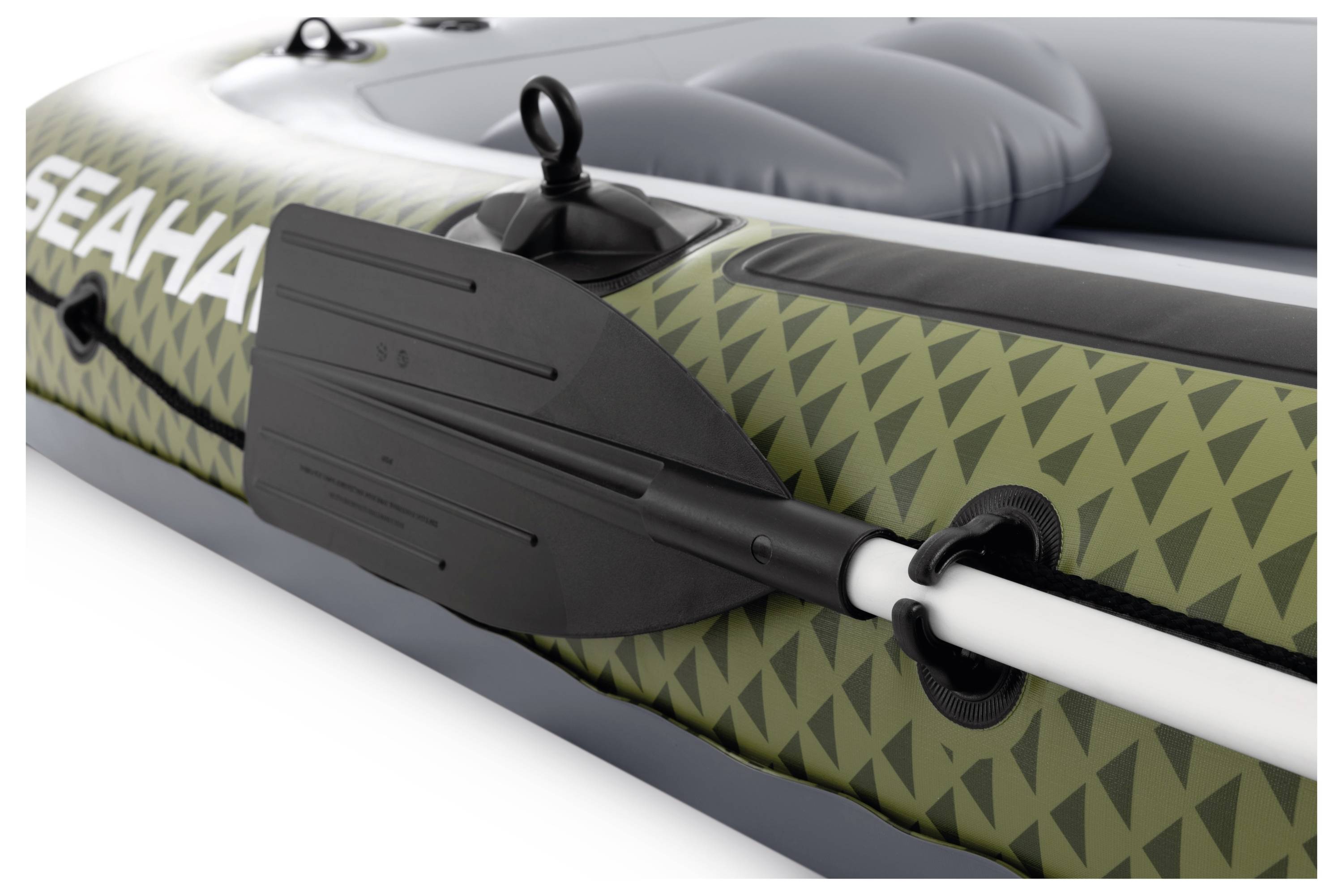 Close-up of a green inflatable boat with a geometric pattern, featuring an attached black paddle, and the partial word 'SEAH' visible.
