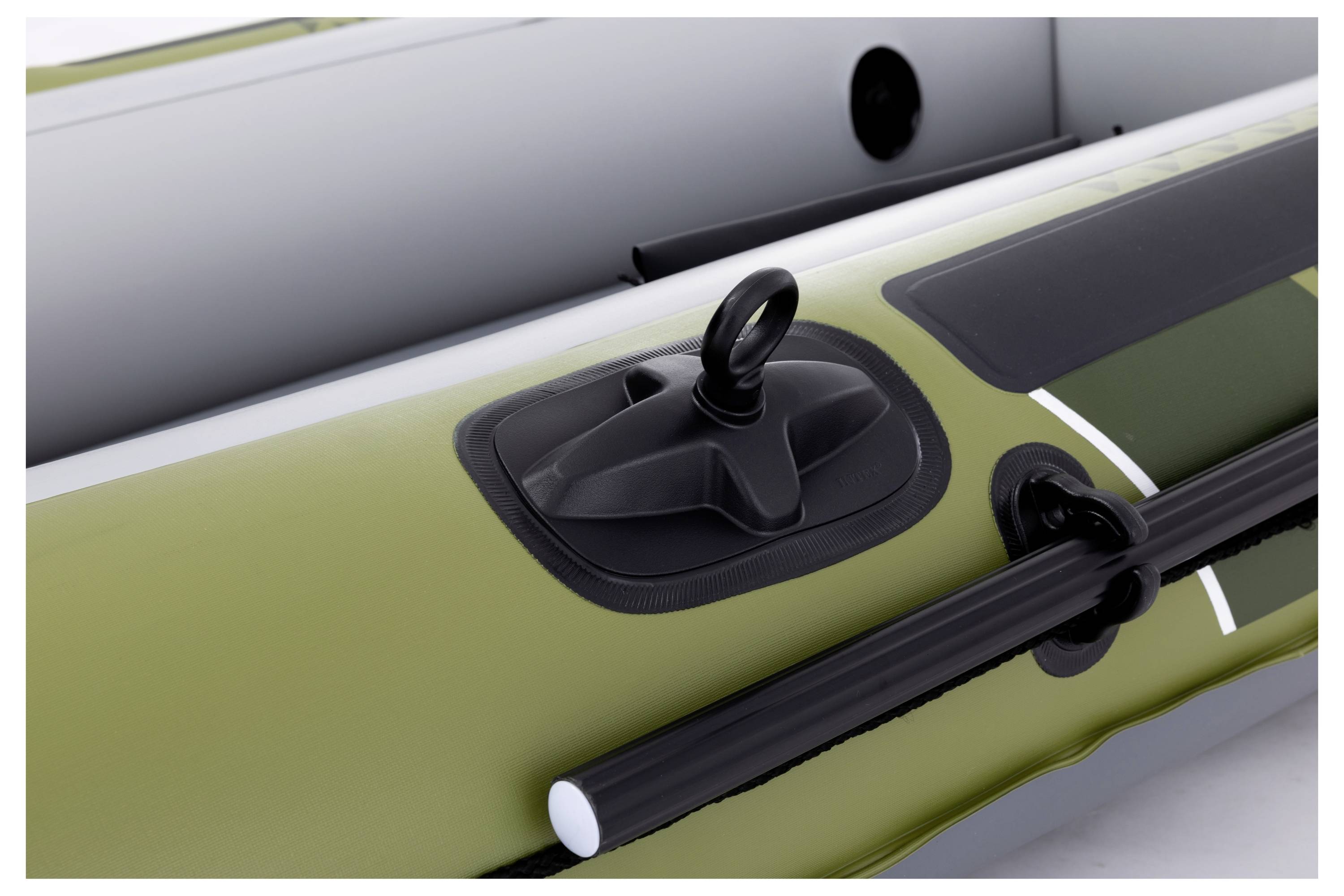 Close-up of an inflatable boat section, showing a mounted oar holder and fastening clips on a green and gray surface.