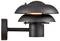 A black, modern wall sconce light fixture with layered circular shades, emitting a warm glow from the center.