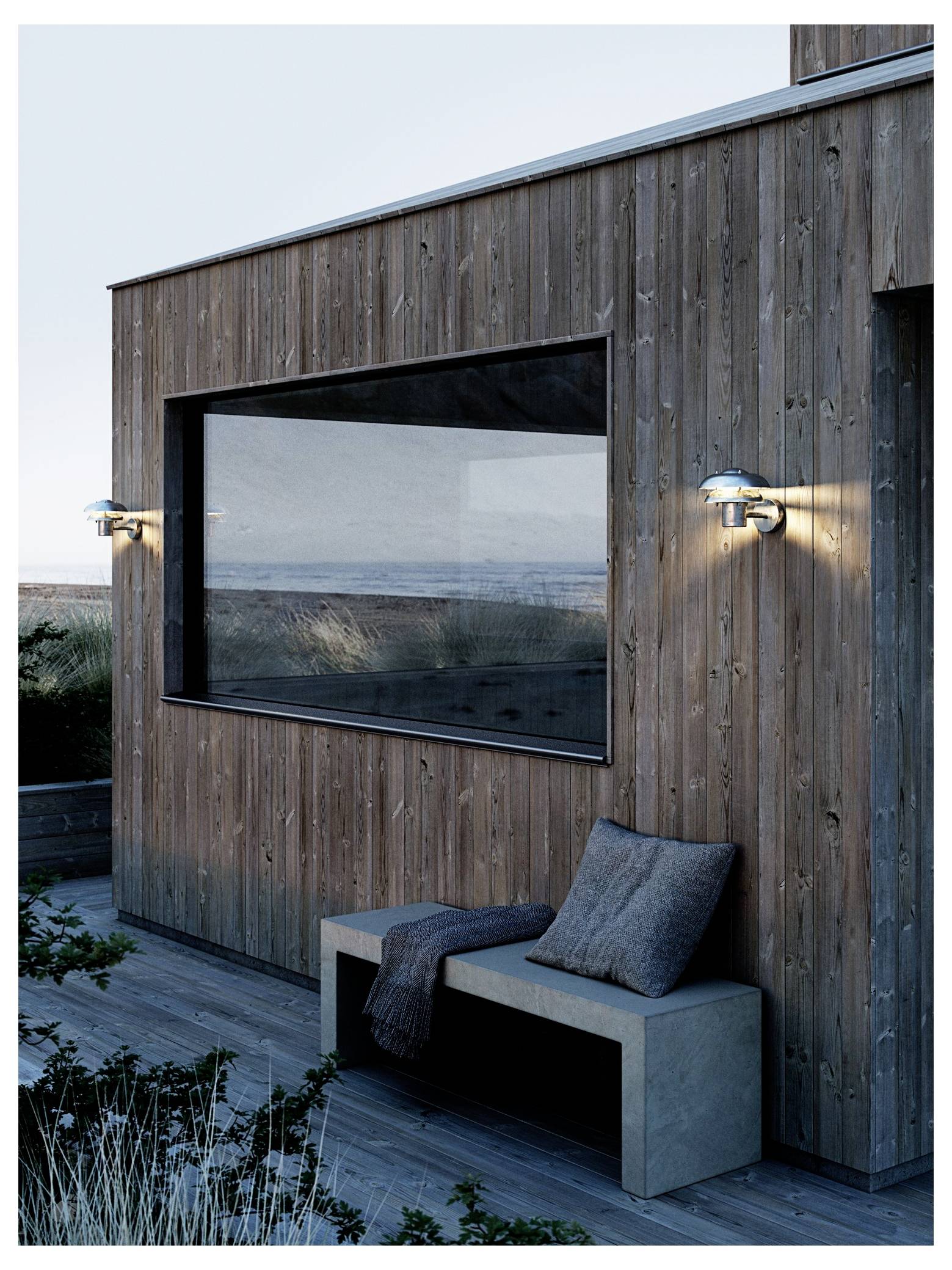 Modern wooden house exterior with large window, outdoor lighting, and bench with cushions; coastal background visible.