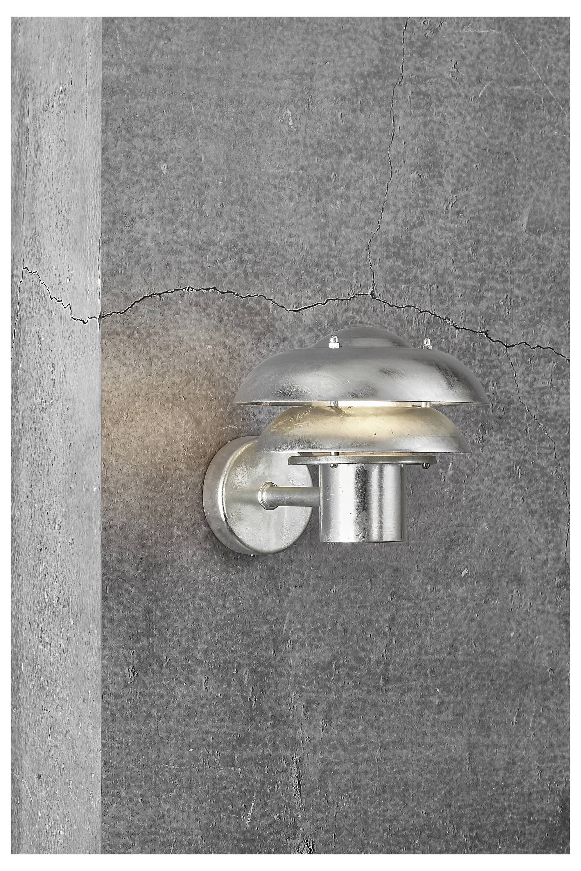 A modern silver wall lamp emits warm light against a textured gray concrete background with a visible crack, highlighting industrial decor.