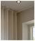 A corner of a room showing beige curtains, a ceiling light, and part of a window with a view of the sky.