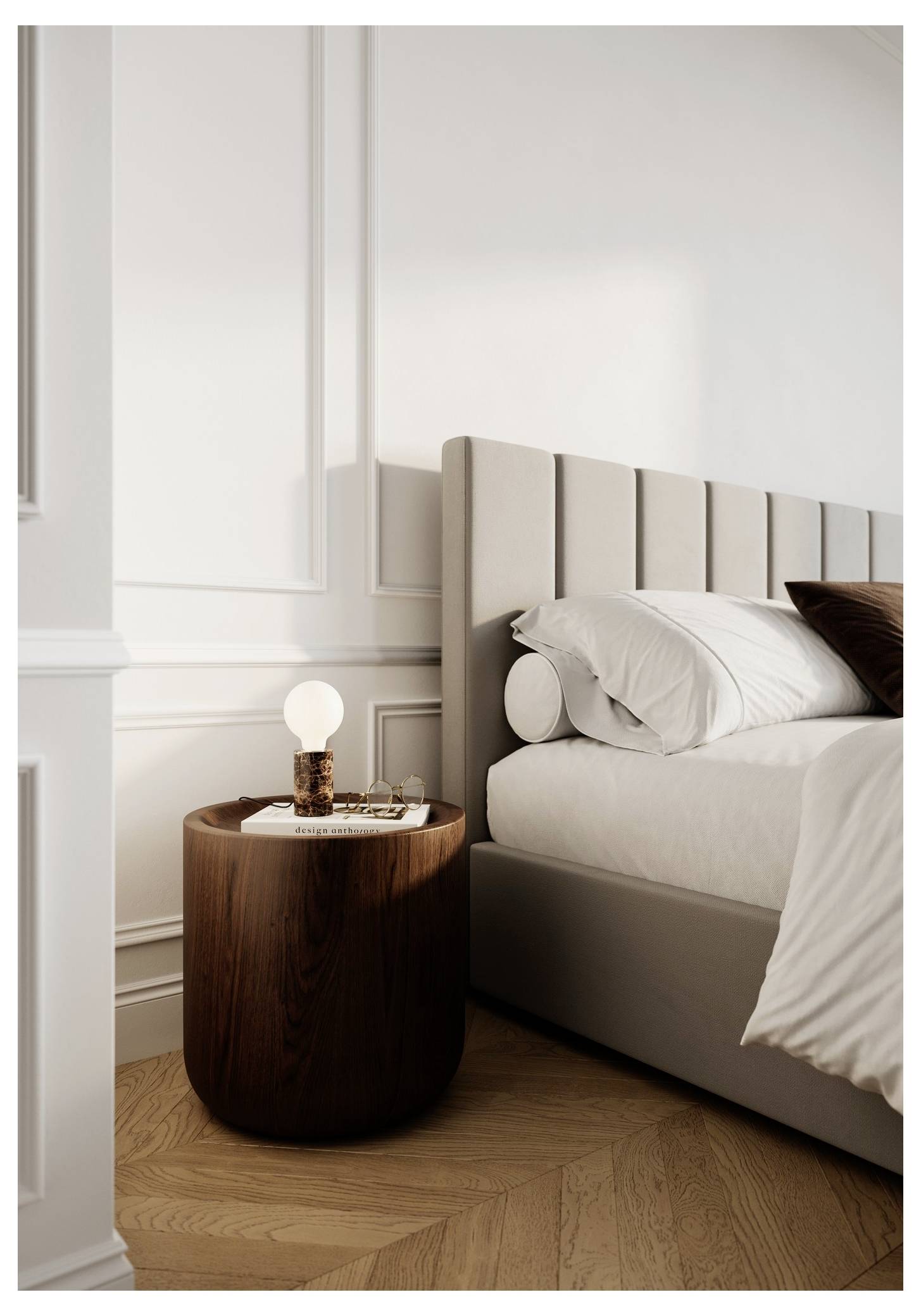 A cozy bedroom features a bed with neutral bedding and a tufted headboard. A wooden nightstand holds a lit lamp and a small book.