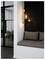 Cozy nook with hanging light bulbs, cushioned bench, and a view into a modern office space with a glass door and chairs.