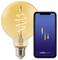 A glowing filament bulb next to a smartphone displaying the 'nordlux smart' app interface, showcasing smart lighting control.