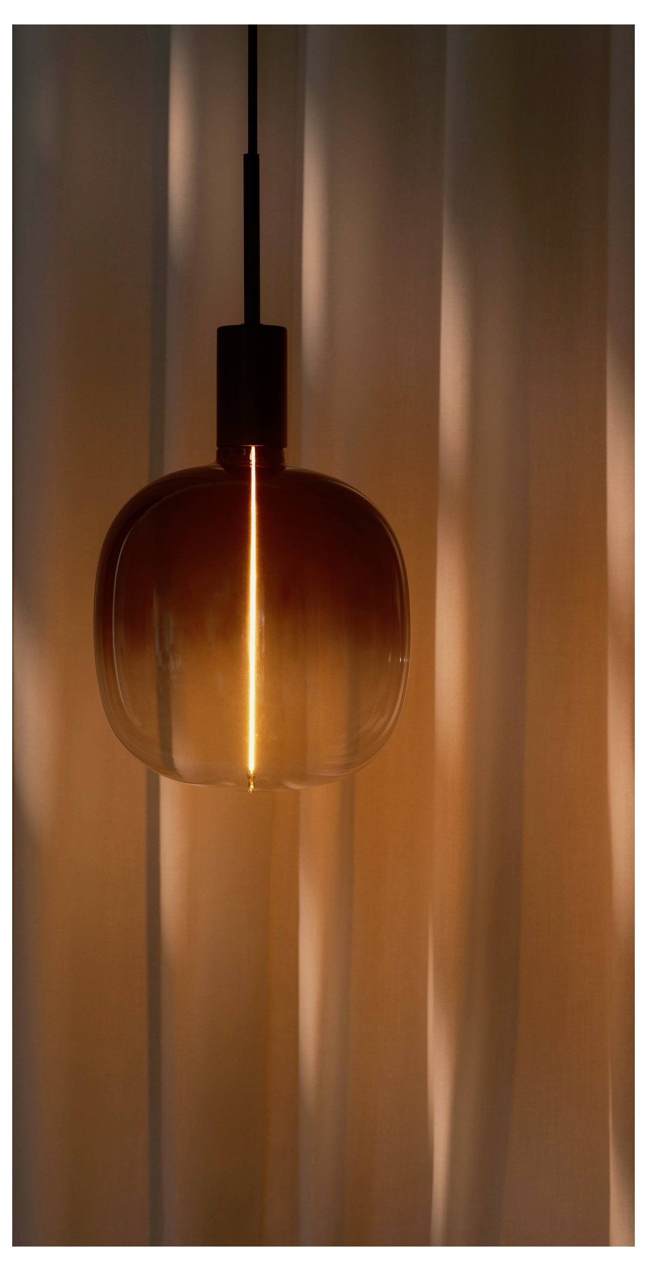 A warm-toned pendant light glows against a softly blurred curtain backdrop, creating a cozy, ambient atmosphere.