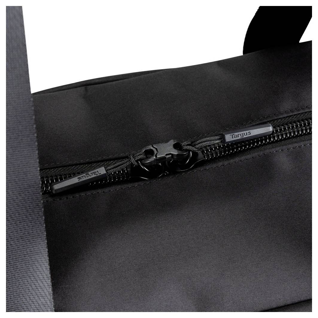 Close-up of a black bag's zipper and pull tabs, showing the front pocket seam and strap edge.<br>