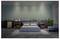 A modern bedroom with a blue upholstered bed, nightstands with decor, and a soft area rug on a concrete floor. A green accent wall adds contrast.