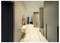 A modern hallway with marble flooring, cream walls, a round mirror, and sleek, floor-to-ceiling cabinets on the right.