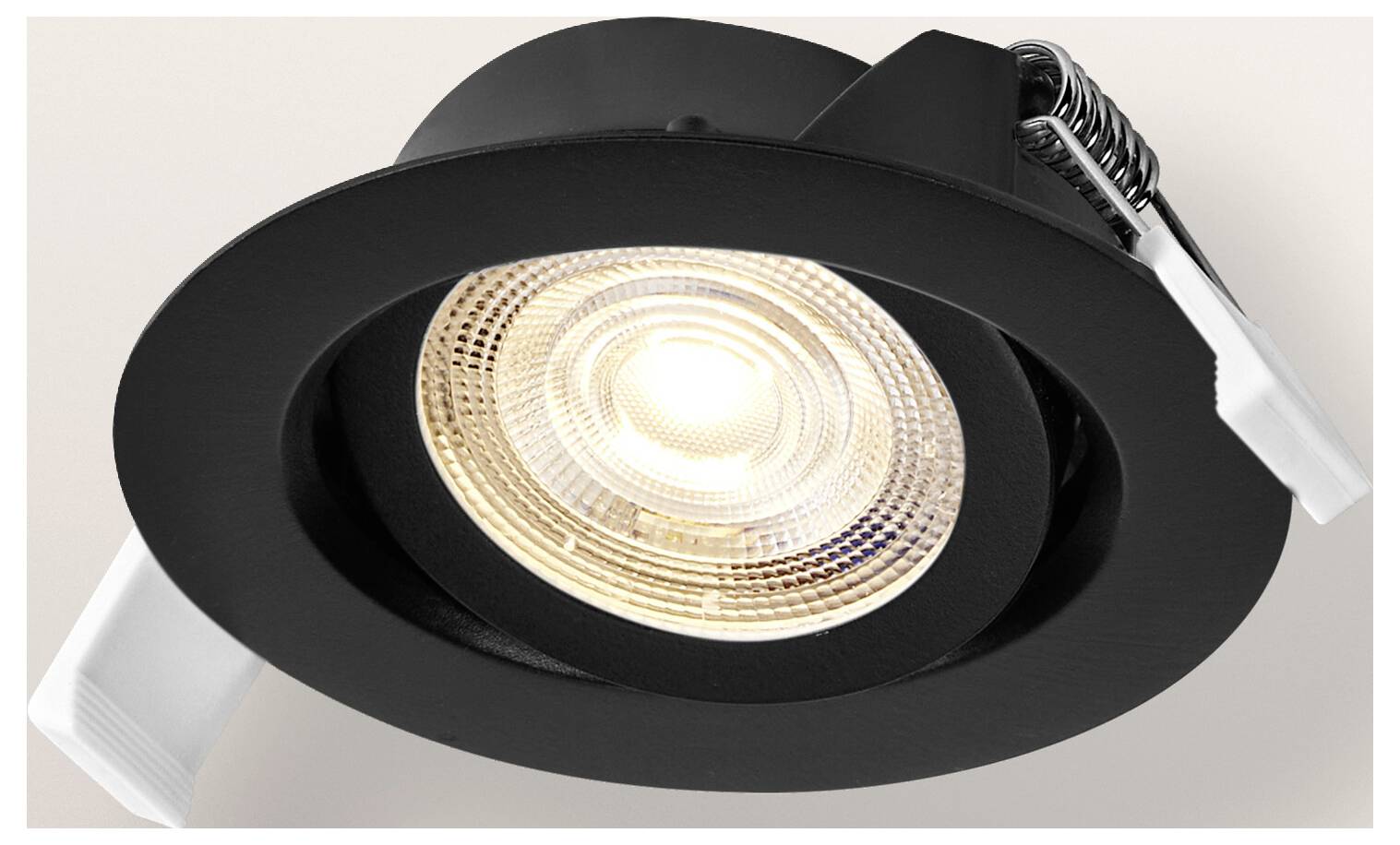 A recessed black ceiling spotlight with a metal trim facing downward, featuring a bright circular LED bulb in the center.