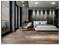 Modern bedroom with gray accent wall, large windows, and minimalist furniture including a white bed, beige chair, and small table.