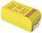 A yellow electronic component, possibly a tantalum capacitor, with red markings and a metal connector on one side.