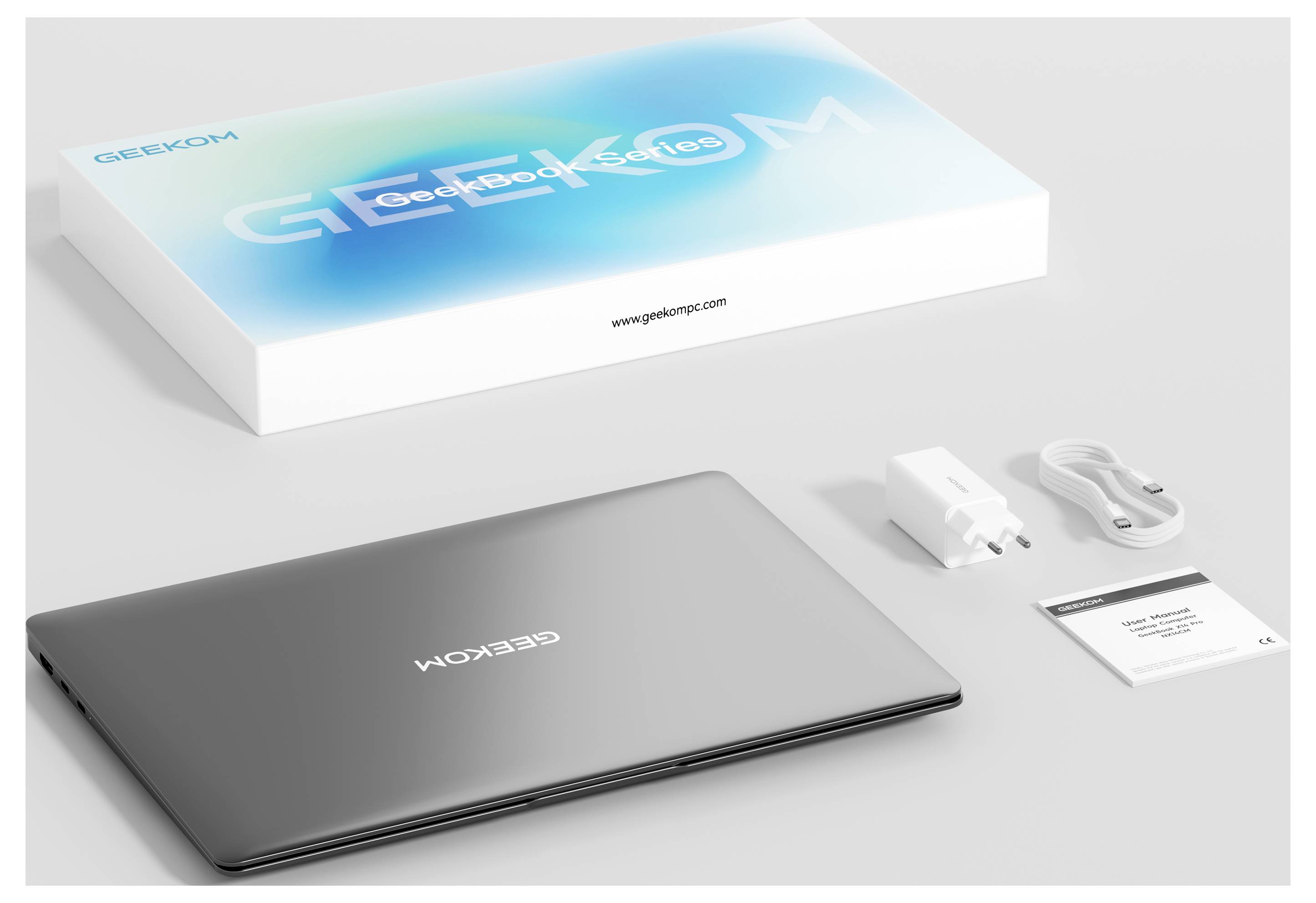 'Laptop with GEEKOM branding alongside a box, USB-C cable, charging adapter, and manual, arranged neatly on a white surface.'