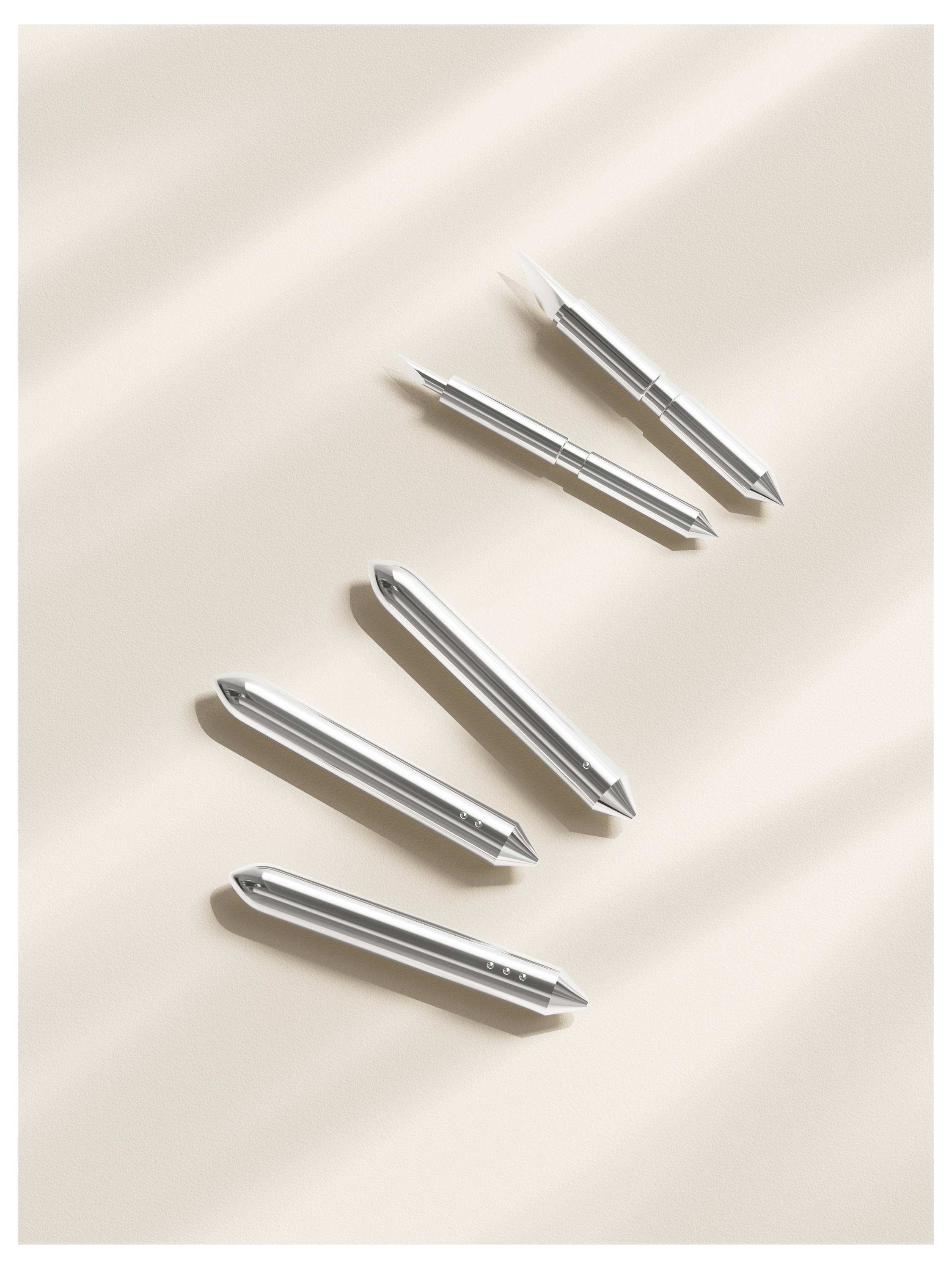 Five silver metallic pens arranged diagonally on a beige surface with soft shadows.