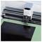 A cutting machine precisely trims a black sheet on a green cutting mat.