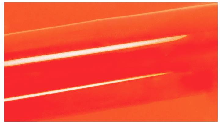 A close-up of a bright red-orange cylindrical object with a smooth texture, reflecting light, set against a matching background.