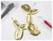 A gold balloon animal dog on a white surface with foil and a red tool nearby.