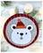 A felt Christmas ornament with a cute polar bear wearing a red Santa hat, surrounded by lights and evergreen branches.