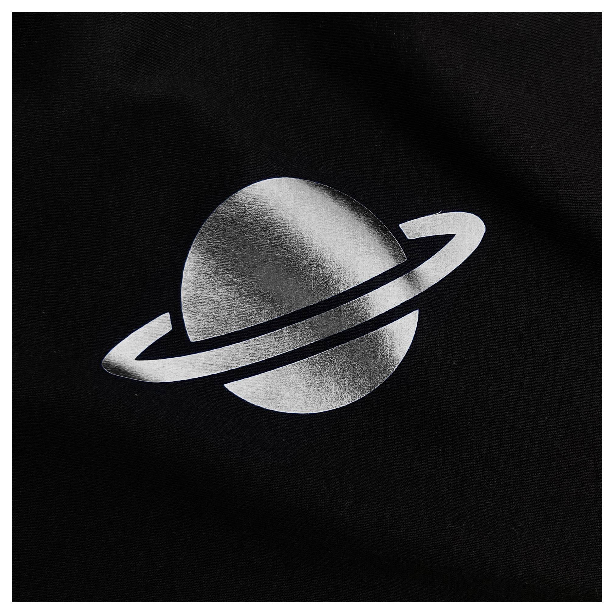 A metallic silver depiction of a planet with rings on a black background, resembling Saturn.