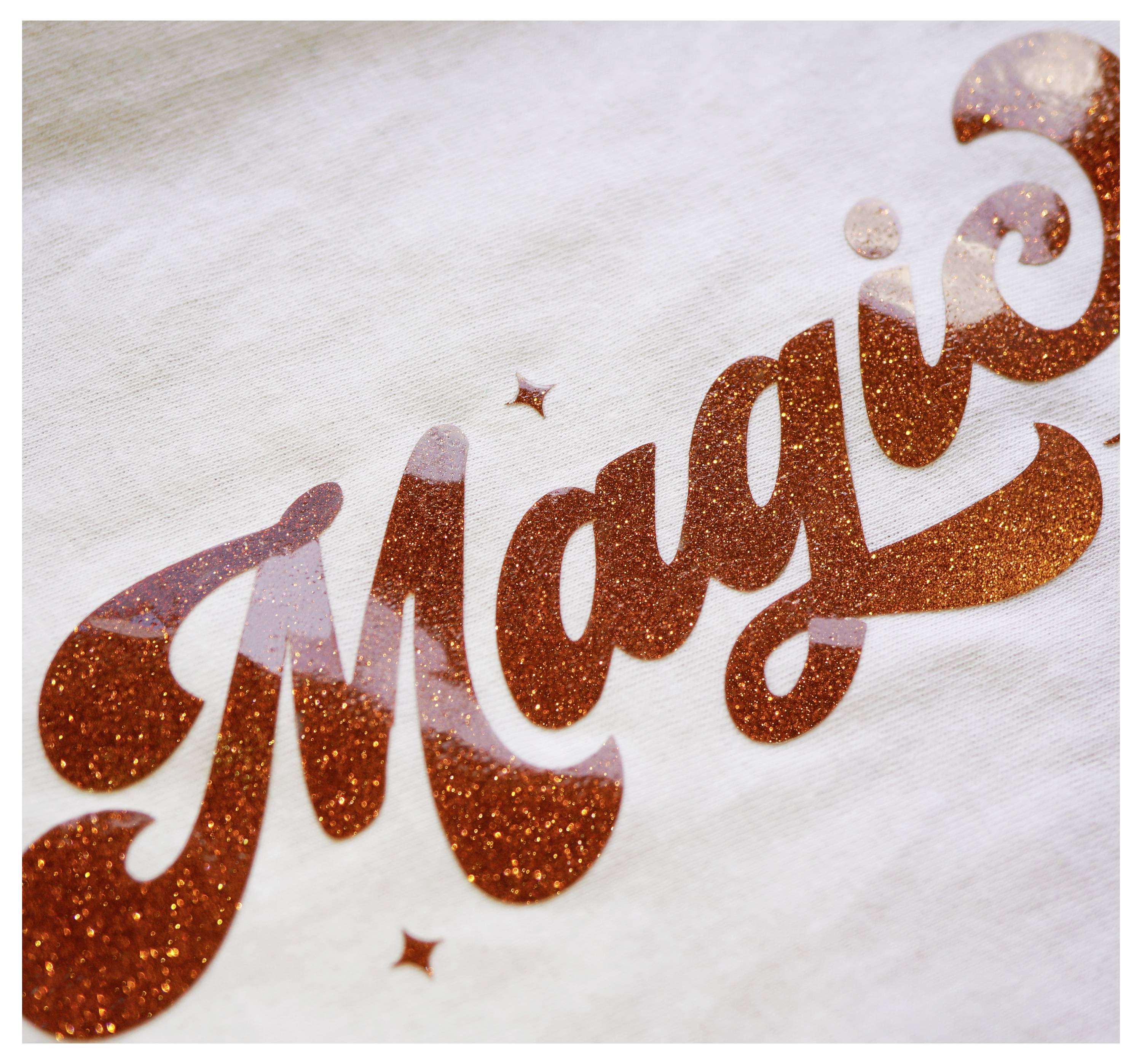 The image shows the word 'Magic' written in sparkling orange letters on a white background.