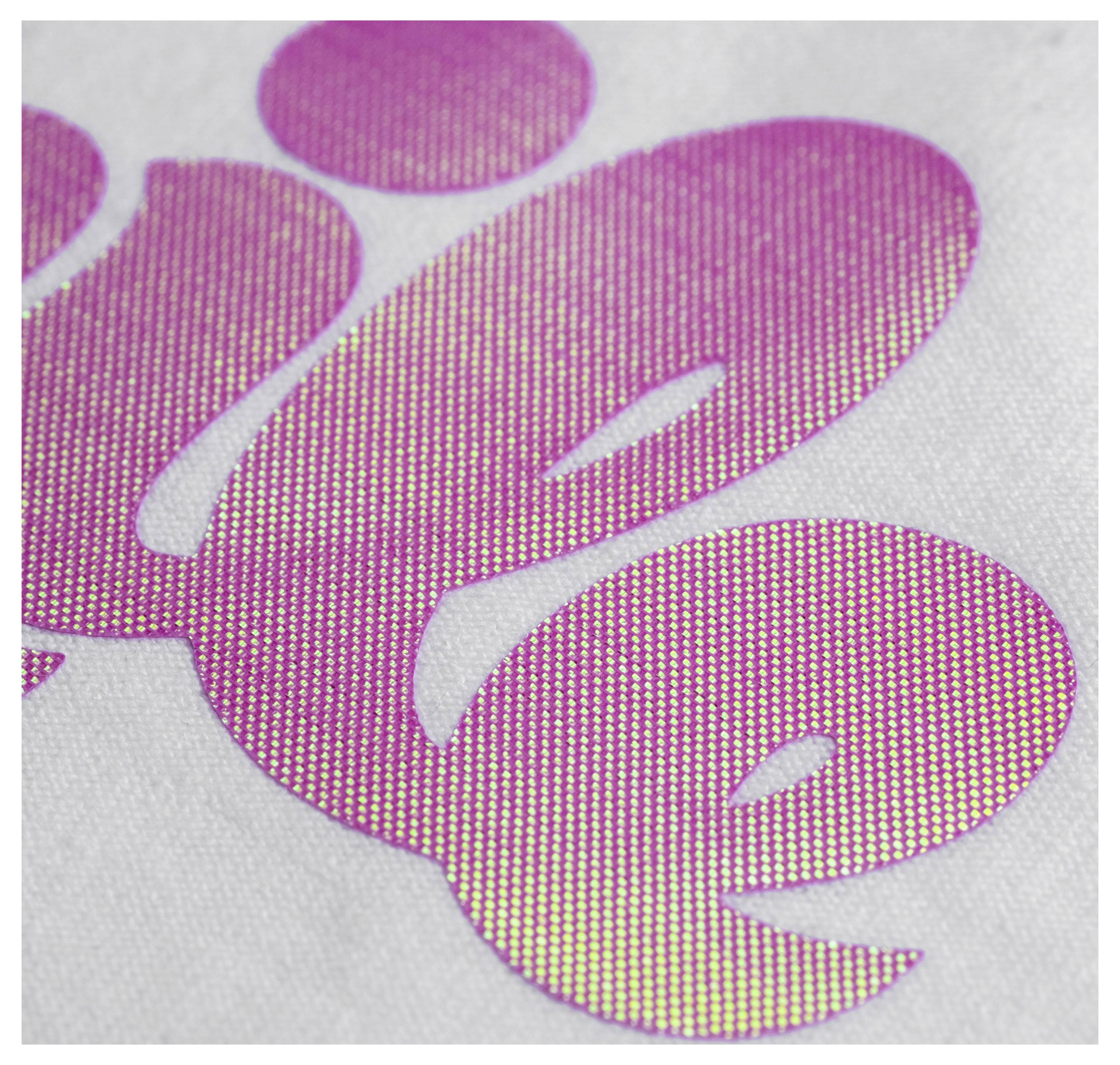 A close-up of vivid pink text with a textured dot pattern on a fabric surface, creating an eye-catching visual effect.
