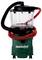 A green and black wet/dry vacuum cleaner with a red hose wrapped around it, featuring clear canisters at the top, on wheels. Brand name 'metabo' visible.