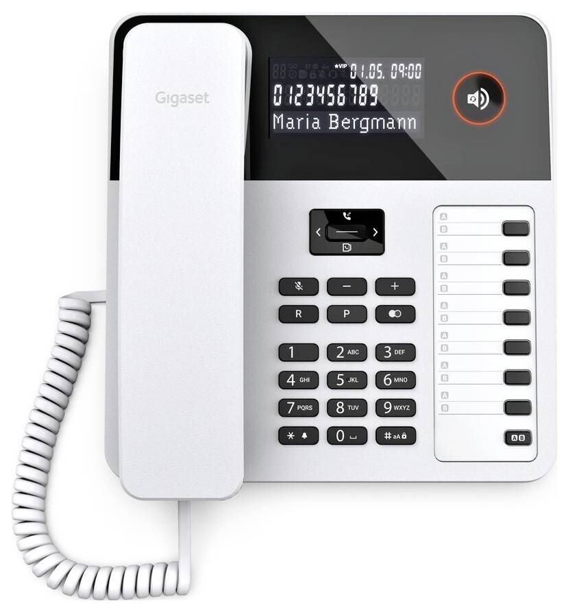 A white corded office phone with a digital display showing 'Maria Bergmann' and the number '0123456789'. Keypad and function buttons visible.