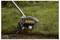 A lawn edger cuts grass along a garden edge, creating a clean boundary between the grass and soil.