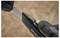 A hand wearing a black glove is holding a utility knife, with the other hand adjusting or replacing its blade, showing precision handling.