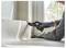 A person wearing gloves is using a utility knife to cut vinyl flooring near a window, ensuring precise alignment and fit.