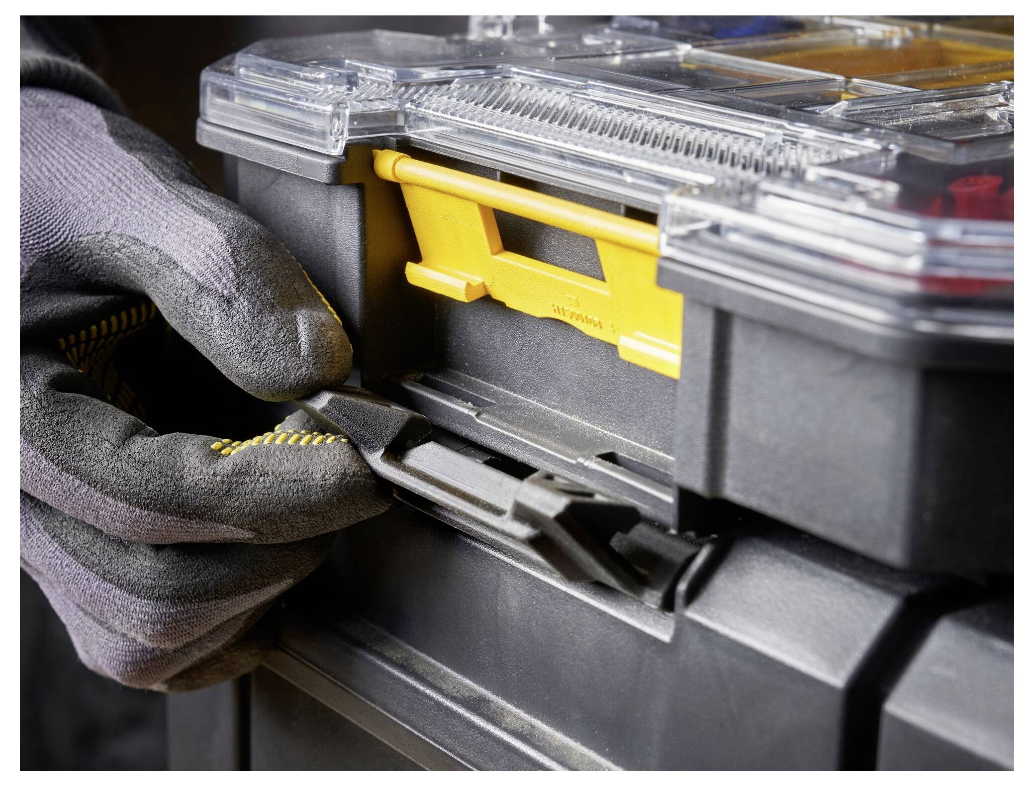 A close-up of a person wearing work gloves latched closed a toolbox, highlighting its durability and secure locking mechanism.
