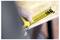 A hand holds a yellow tape measure extended several inches, focusing on precise measurement against a blurred wood surface background.