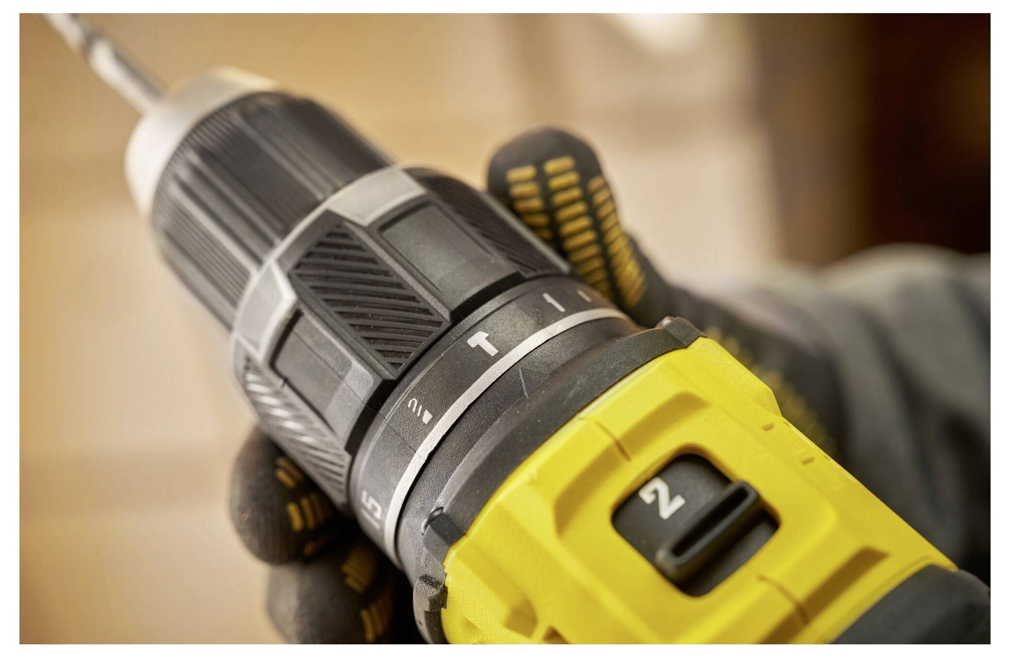 Close-up of a hand holding a cordless drill with focus on the drill's settings and grip, highlighting its use in construction or DIY tasks.
