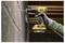 'A person uses a yellow cordless power drill to make a hole in a concrete wall, wearing a glove for safety.'