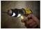 A person uses a yellow cordless drill to make a hole in a wall, with the drill's light illuminating the surface.