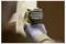 A person wearing a glove uses a yellow brushless power drill on a light wooden surface.