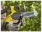 A person wearing gloves holds a yellow and black hand chainsaw with visible details on its blade, set outdoors against a green, blurred background.