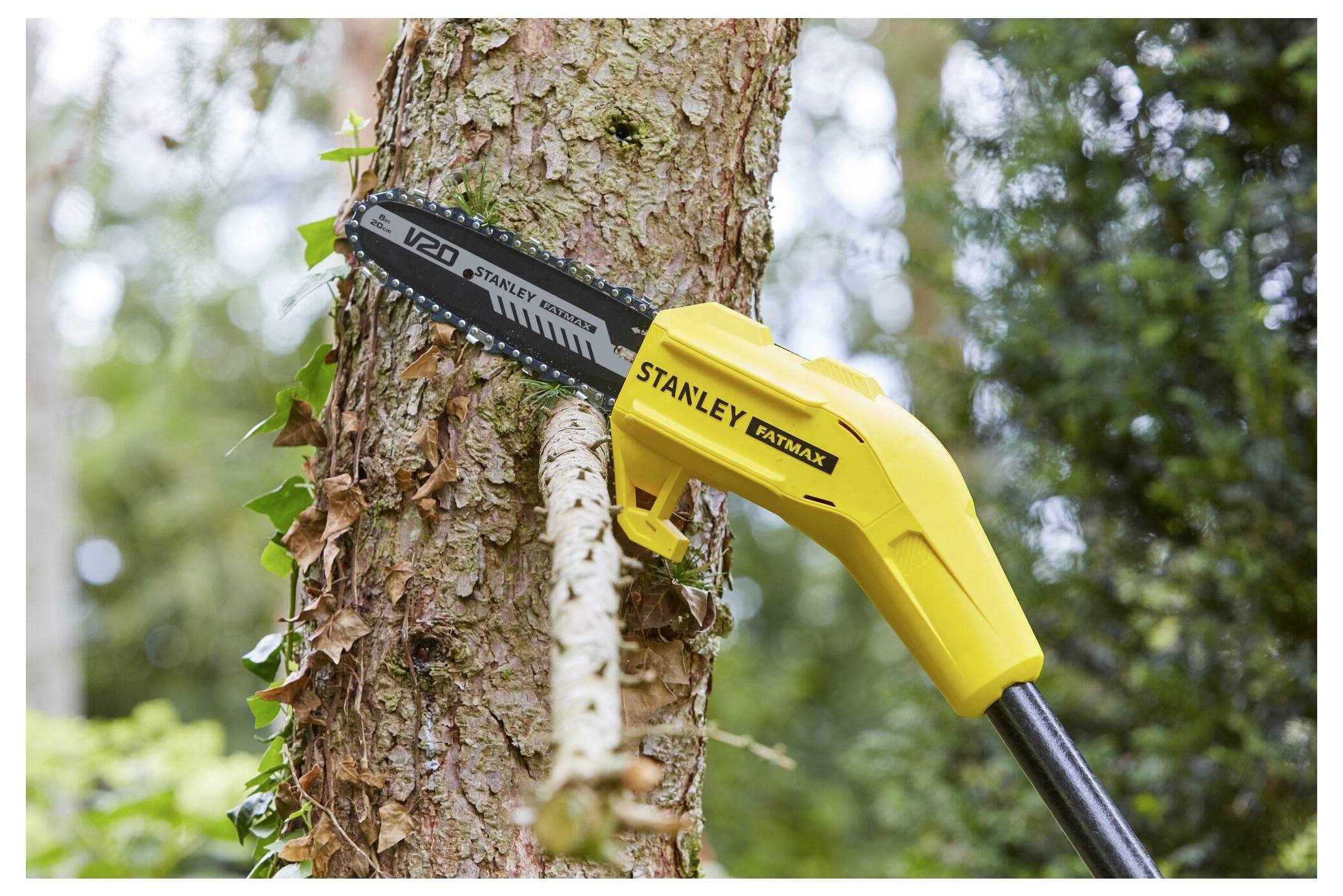 A yellow chainsaw cutting into a tree branch, surrounded by greenery, showcasing its use in outdoor gardening or tree maintenance.