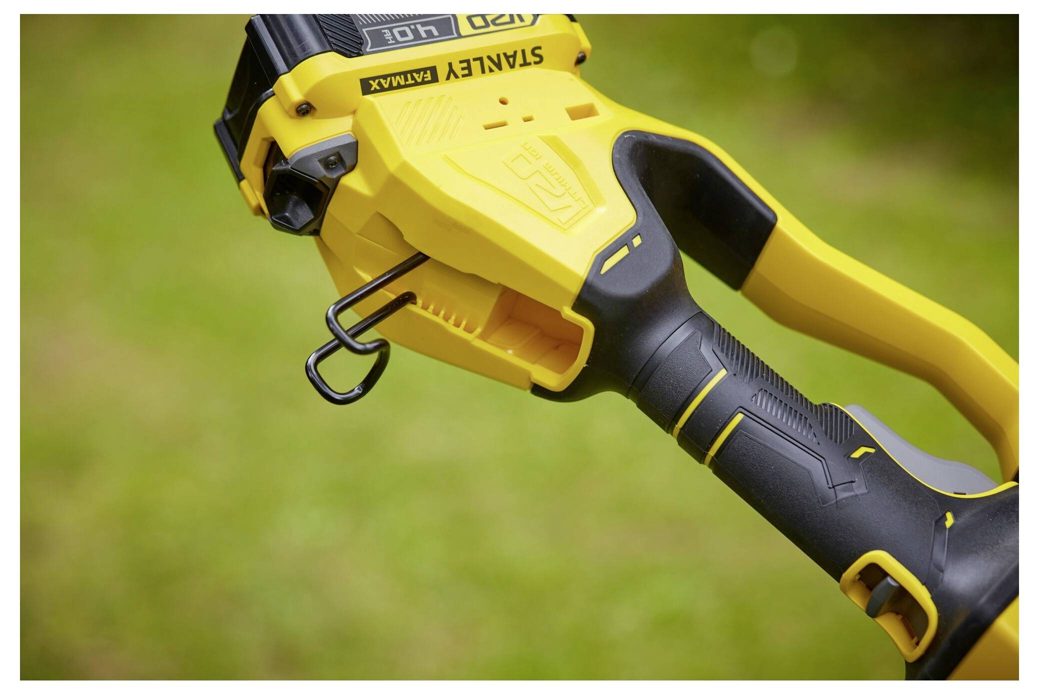 Close-up of a yellow and black Stanley FatMax power tool on a grassy background, emphasizing its ergonomic handle and robust design.