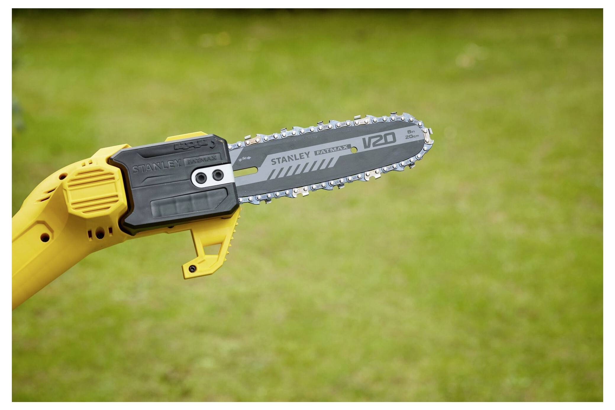 A yellow electric chainsaw with 'Stanley Fatmax V20' branding on the blade, held against a green grass background.