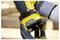 A person wearing gloves inserts a yellow and black battery into a power tool, preparing for use during construction work.