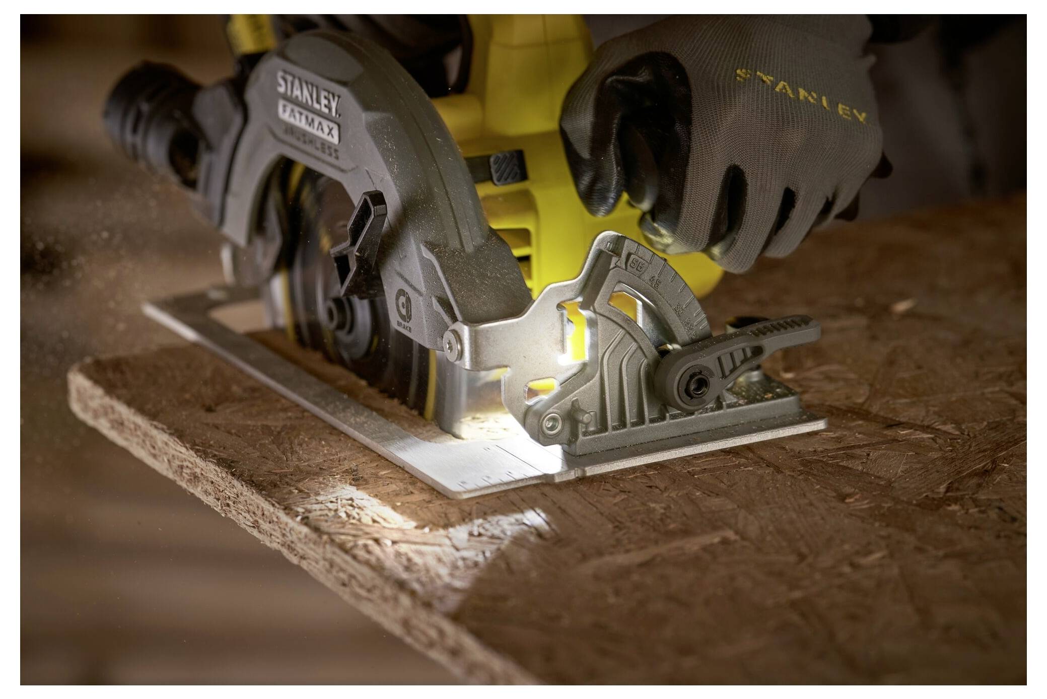 A person uses a circular saw to cut a piece of wood, with sawdust visible. The tool is held firmly, and light highlights the cutting edge.