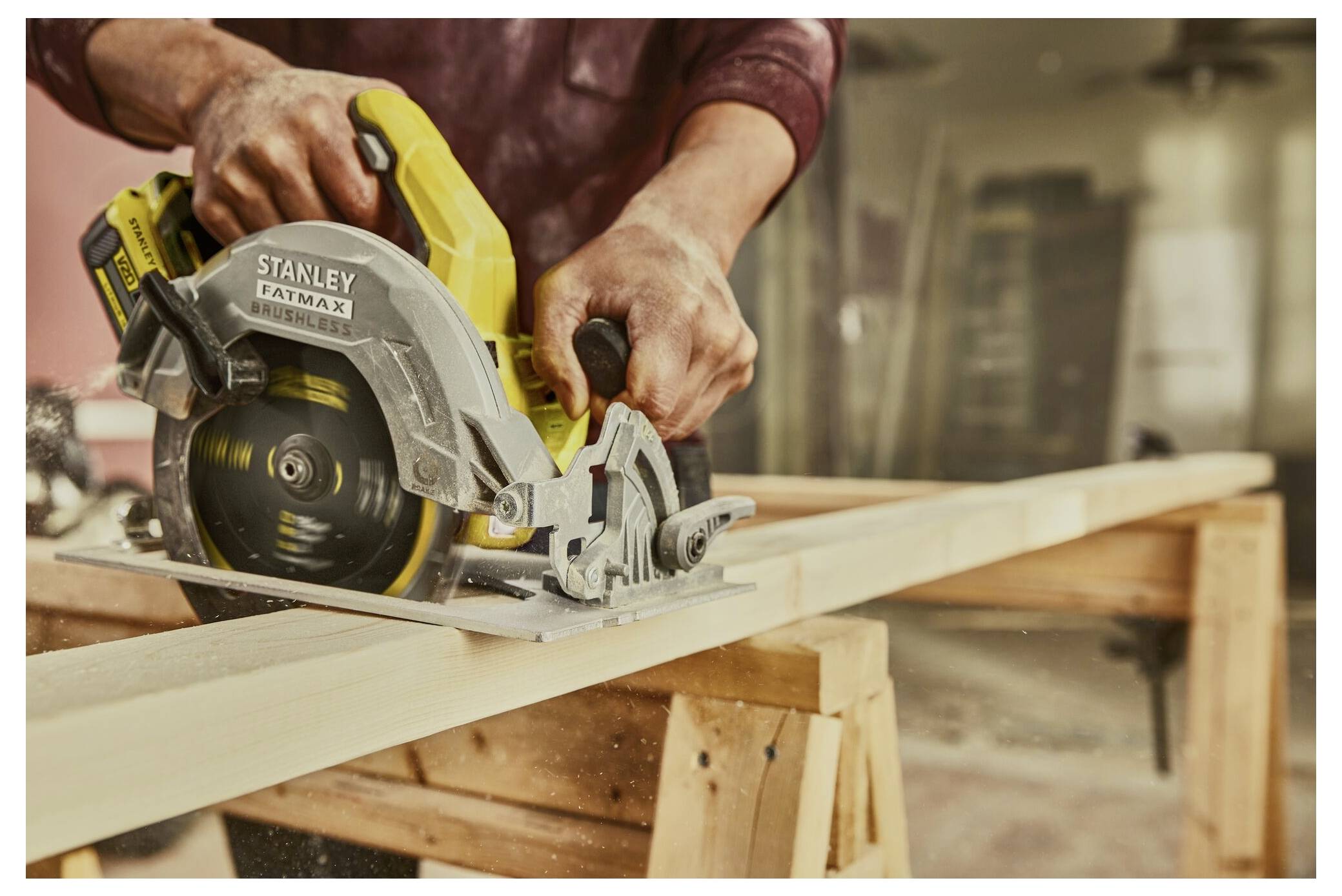 A person uses a circular saw to cut a wooden plank on a workbench in a workshop.