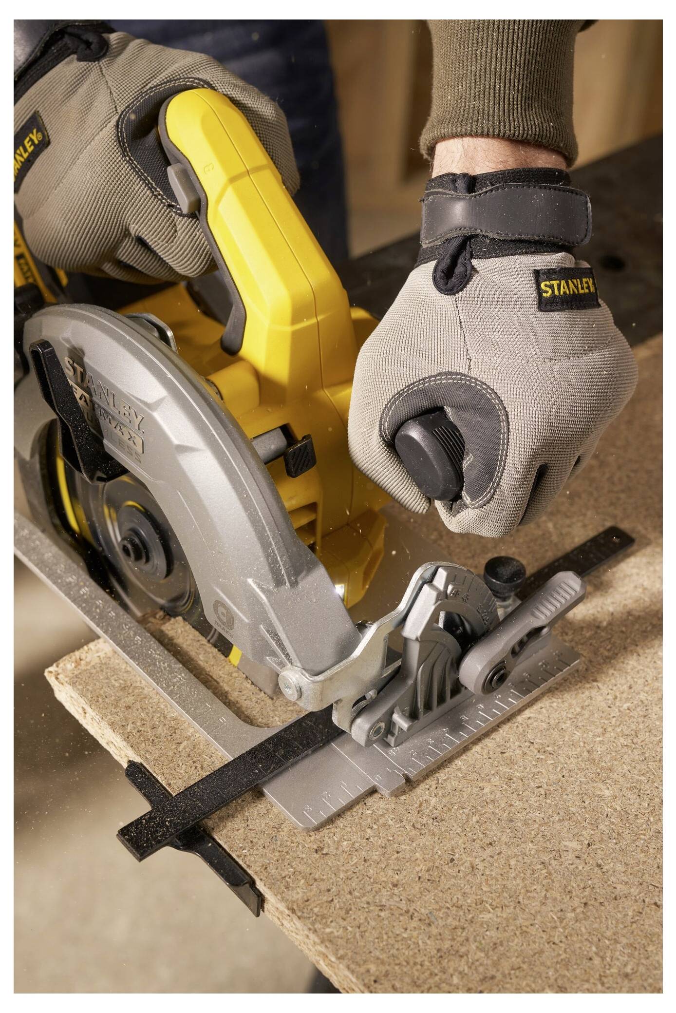 'A person using a yellow circular saw to cut a piece of wood. The person wears gray gloves for safety.'