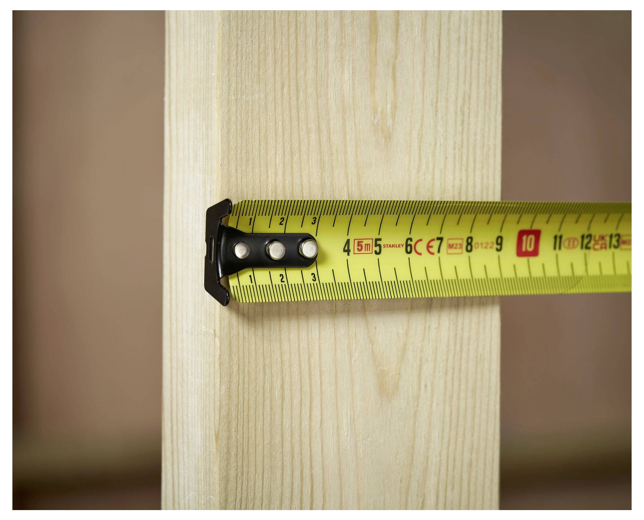 A yellow tape measure shows a measurement of 8 cm on a vertical wooden beam, highlighting the beam's width.