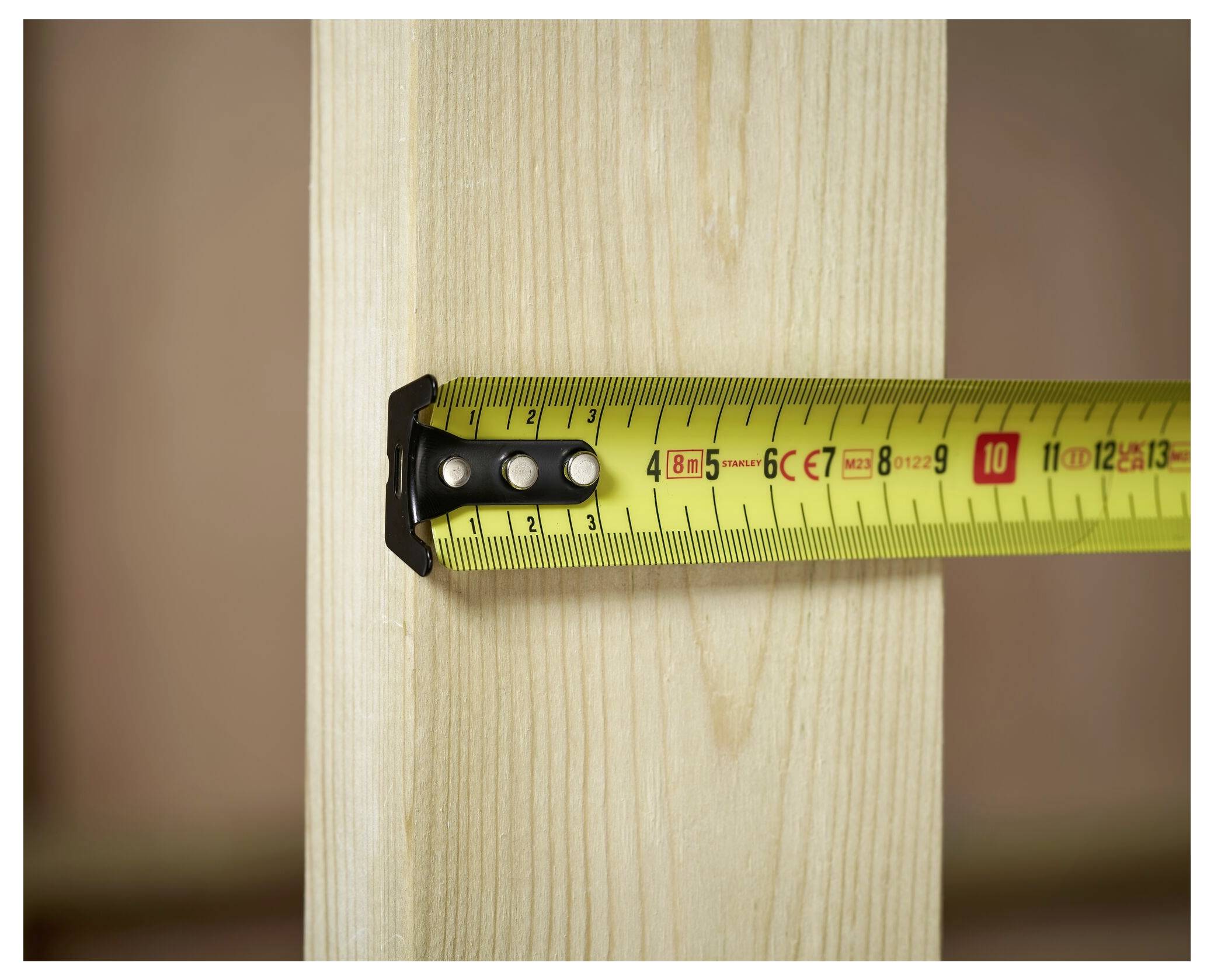 A tape measure wrapped around a wooden beam, indicating a width measurement of approximately 6.5 centimeters.